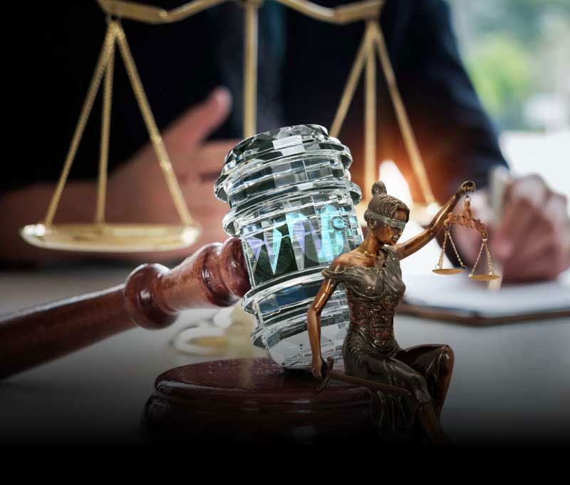 Captured from the viewpoint of a client seated across the desk, the photo showcases a lawyer’s workspace adorned with golden scales, a crystal gavel, and a miniature statue of Lady Justice.
