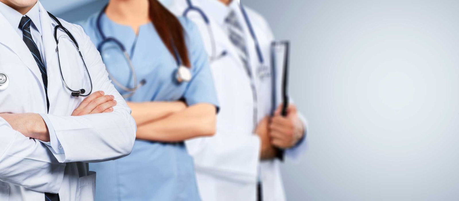 Three doctors, two males and one female, are confidently standing in-line in a brightly lit area.