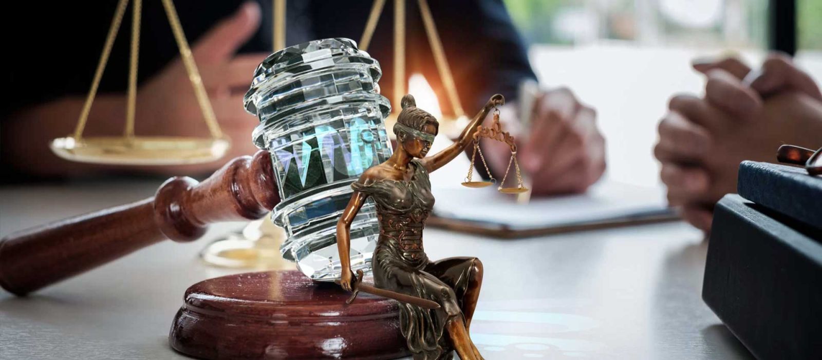 Captured from the viewpoint of a client seated across the desk, the photo showcases a lawyer’s workspace adorned with golden scales, a crystal gavel, and a miniature statue of Lady Justice.